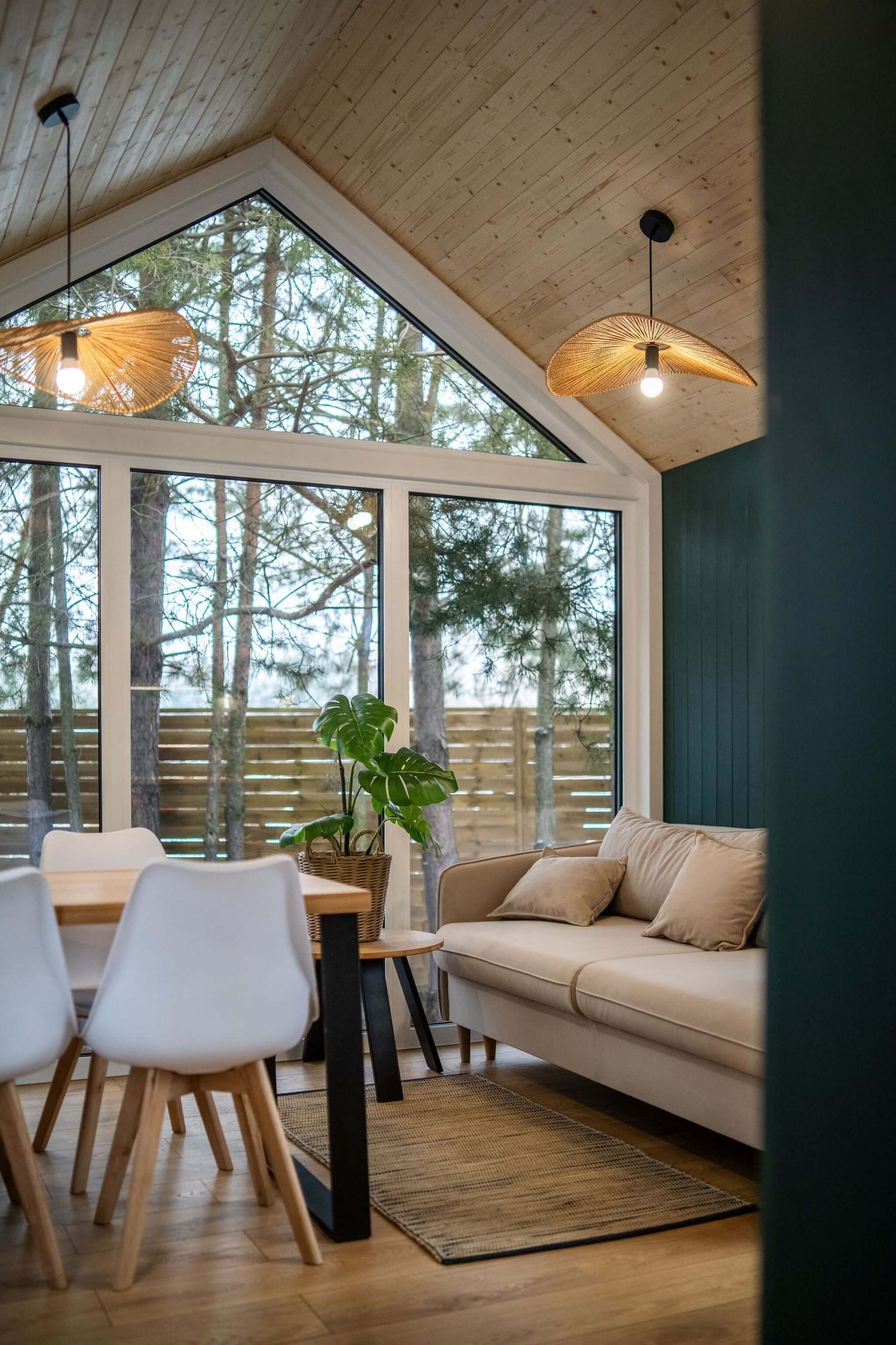 Modernes Tiny House mit grosser Fensterfront, Essbereich und gemütlichem Sofa im skandinavischen Stil.